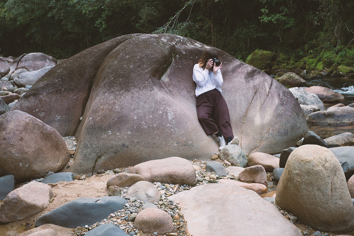 Juliana é registrada com grandes pedras ao fundo enquanto fotografa.