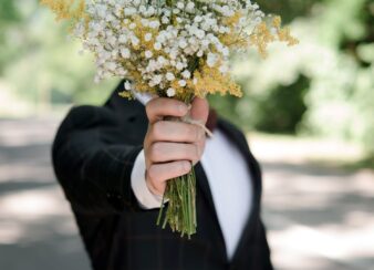Homem segurando um buquê de flores à frente do rosto.