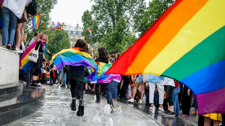 Foto de pessoas em um pequeno palco durante uma marcha no dia do orgulho LGBTQIAP+
