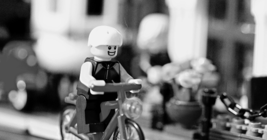 Na imagem, um boneco de lego dirige uma motocicleta e tem o rosto feliz.
