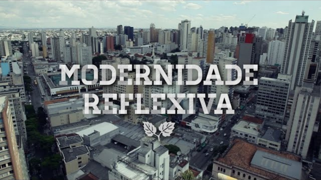 Foto aérea da cidade de Curitiba com vários prédios e o nome modernidade reflexiva no centro na cor cinza. 6 documentários para uma vida inspiradora e com propósito