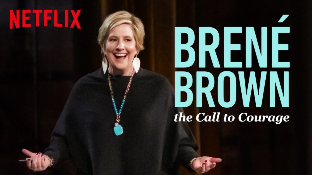 Foto da capa do documentário de Brené Brown, Call to Corage. Ela está sorrindo, usa brincos na cor branca, um colar longo azul e um vestido preto. 6 documentários para uma vida inspiradora e com propósito 