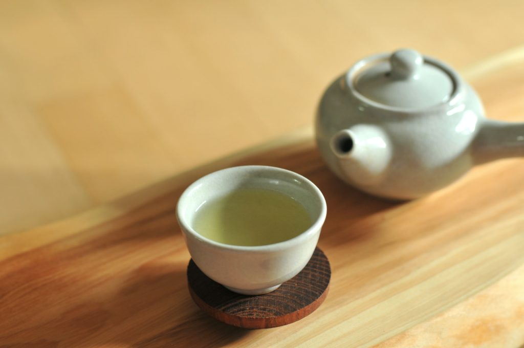 xícara com chá verde e uma chaleira de louça ao lado. Tipos de chás e seus benefícios