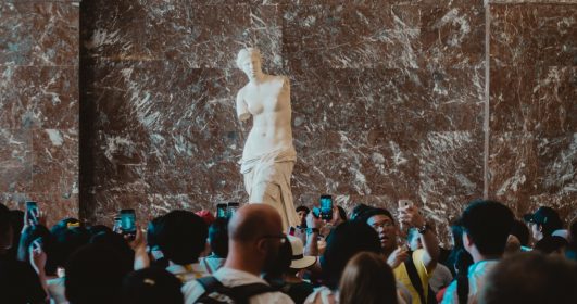 imagem de pessoas tirando fotos selfie em frente a uma estátua em um museu.