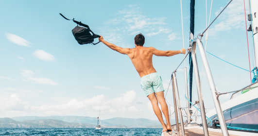 Um homem de pele branca e calção está um barco no meio do mar com uma bolsa no ar. Minimizar, um verbo com benefícios