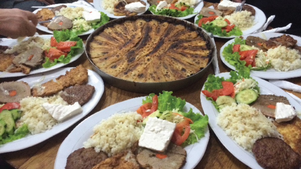 pratos típicos de Kosovo, país europeu, há carnes, salada, queijo e arroz.