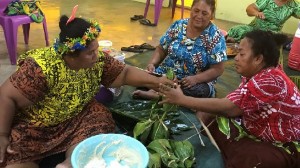 mulheres estão sentadas no chão produzindo um alimento nativo de Tuvalu