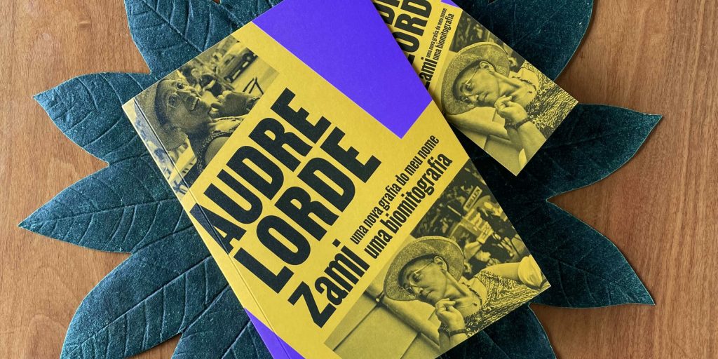 Foto de um livro com capa azul e amarelo, o nome Audre Lorde destacado e Zami mais embaixo. biografia