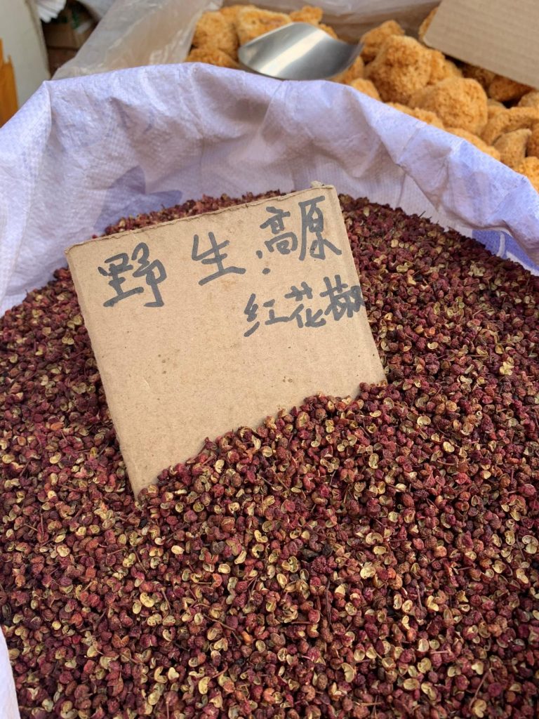 Saco de pimenta Sichuan, feira de Lijiang, China. Ela está em grãos com uma cor avermelhada e uma placa de pamelão sinalizando