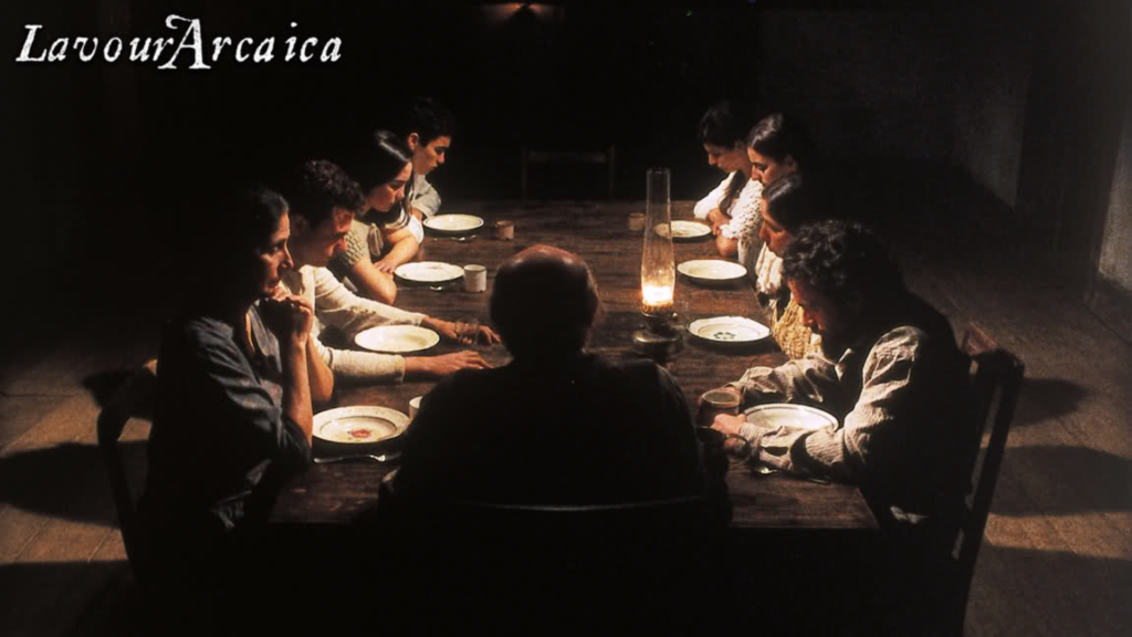 Uma familia se alimenta em uma mesa de madeira, com pratos de louça, copos de vidro e usando roupas brancas. filmes