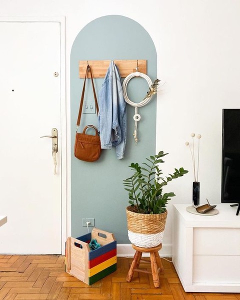 um hall de entrada com vaso de plantas, cabide de roupas e um papel de parede azul.