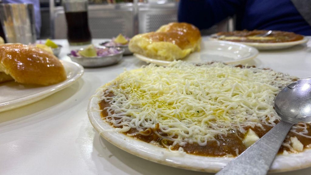 foto de um prato de comida na cor marrom com queijo ralado em cima do alimento