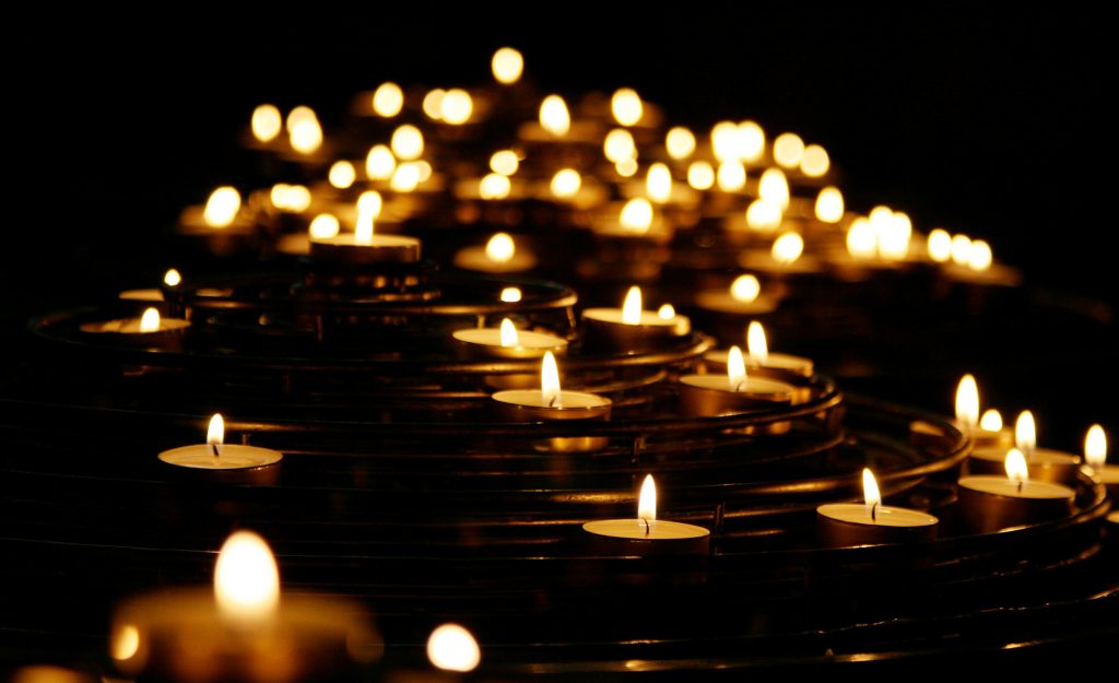 Fases do luto não são lineares. Na foto, várias velas acessas em diferentes pontos da foto, sem ordem e num ambiente escuro.