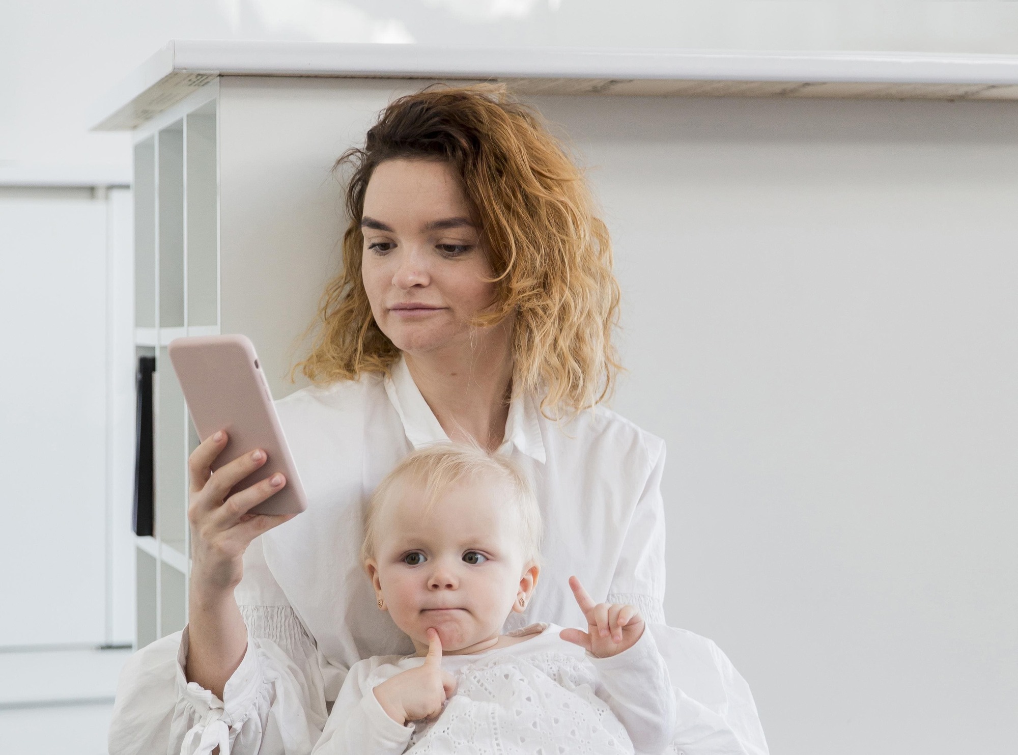 Mãe com celular na mão e o bebê no colo